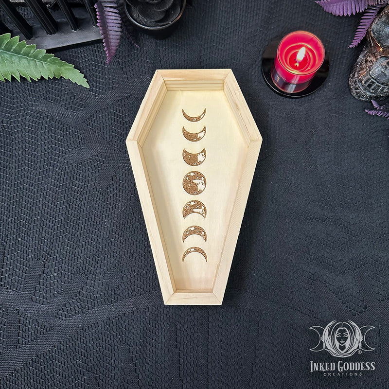 Load image into Gallery viewer, A coffin-shaped wooden tray with a moon phase design, displayed on a black textured cloth with a red candle and mystical props.
